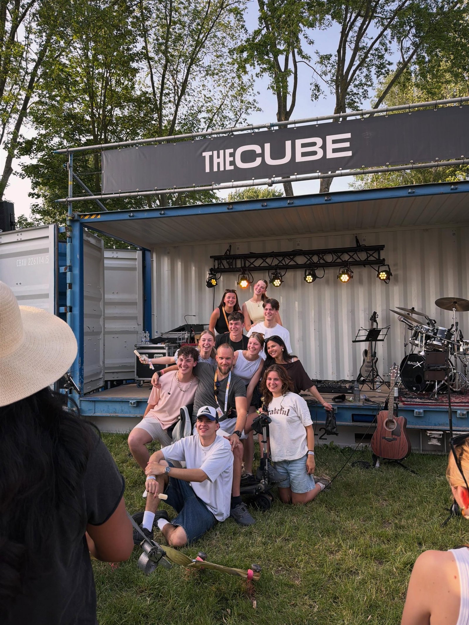 De hele band, lachend voor het containerpodium The Cube op Opwekking